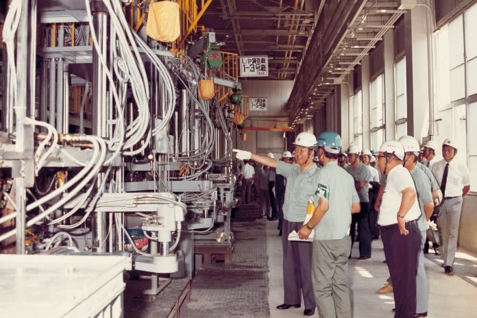 Ingénieurs Yamaha casqués visitant la ligne de fonderie de l'usine numéro 3 d'Iwata au début des années 1980