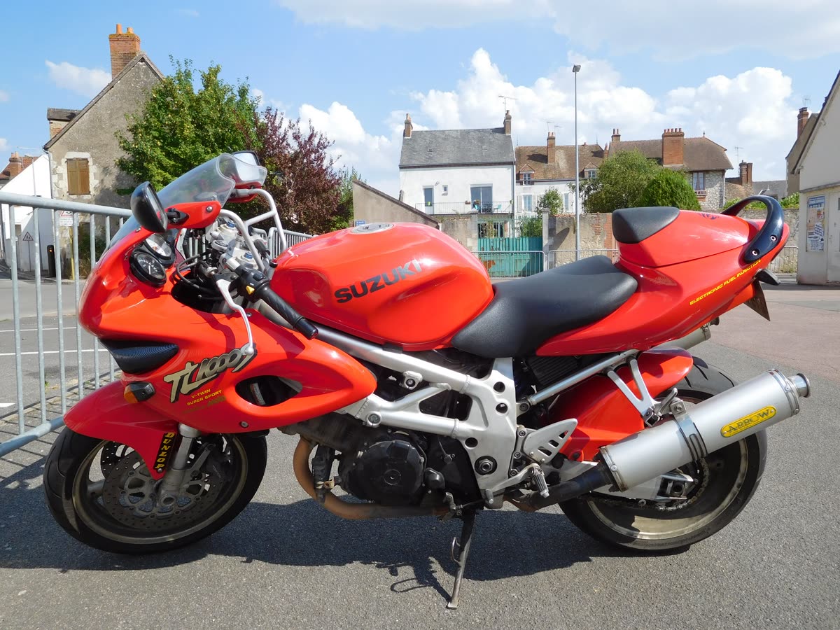 Suzuki TL1000S rouge vue de profil gauche, garée sur la place d'un village