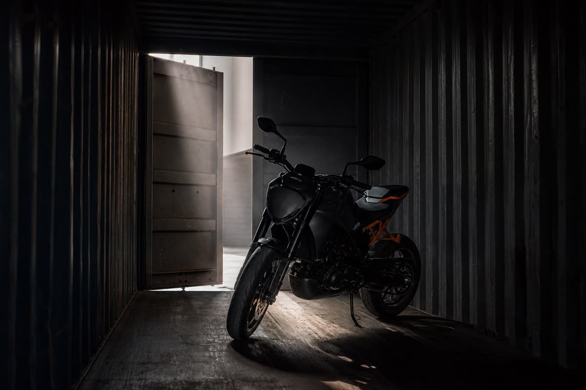 Moto seule dans un conteneur métallique sombre, éclairée par un rai de lumière venu de la porte entrouverte