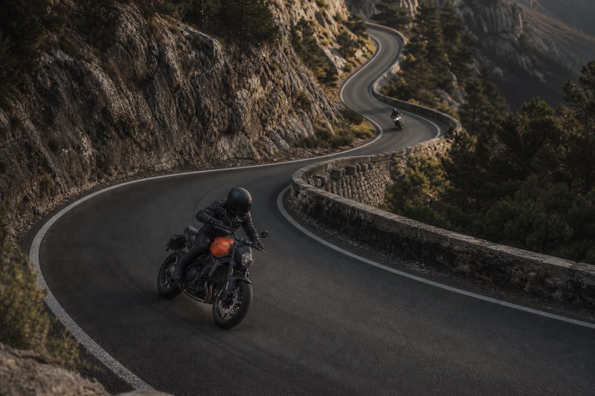 Deux motos roadster qui se suivent à distance sur une route de montagne en lacets